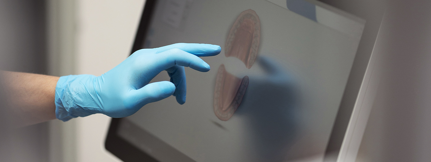 Gloved hand pointing at a dental image on a touchscreen display in Des Moines IA