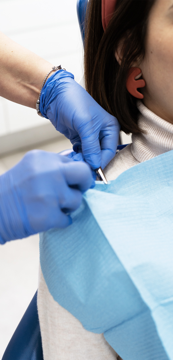 "A close-up of a dentist's gloved hands holding dental instruments, preparing for a procedure on a patient covered with a protective bib in Des Moines IA