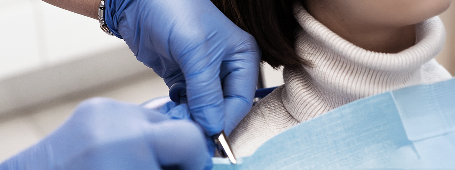 Dentist wearing blue gloves and preparing tools for a patient in a dental bib in Des Moines IA